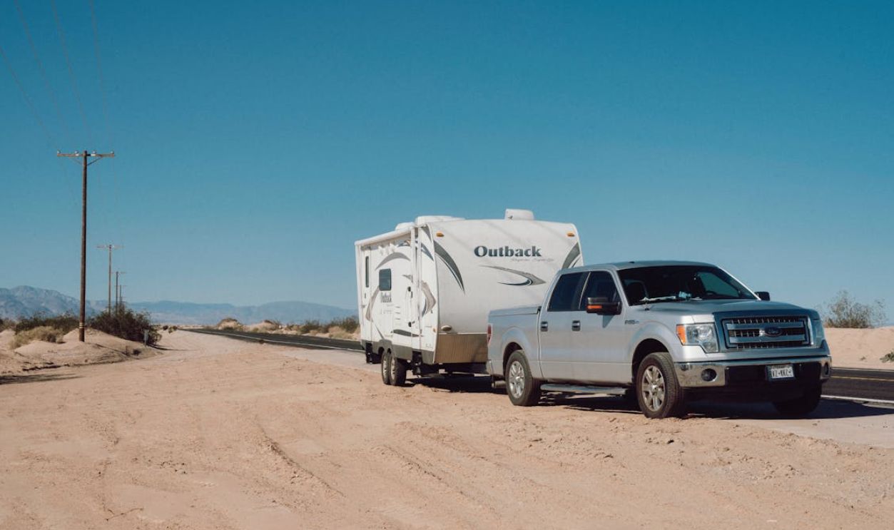 Silver Car with Trailer on Arid Road