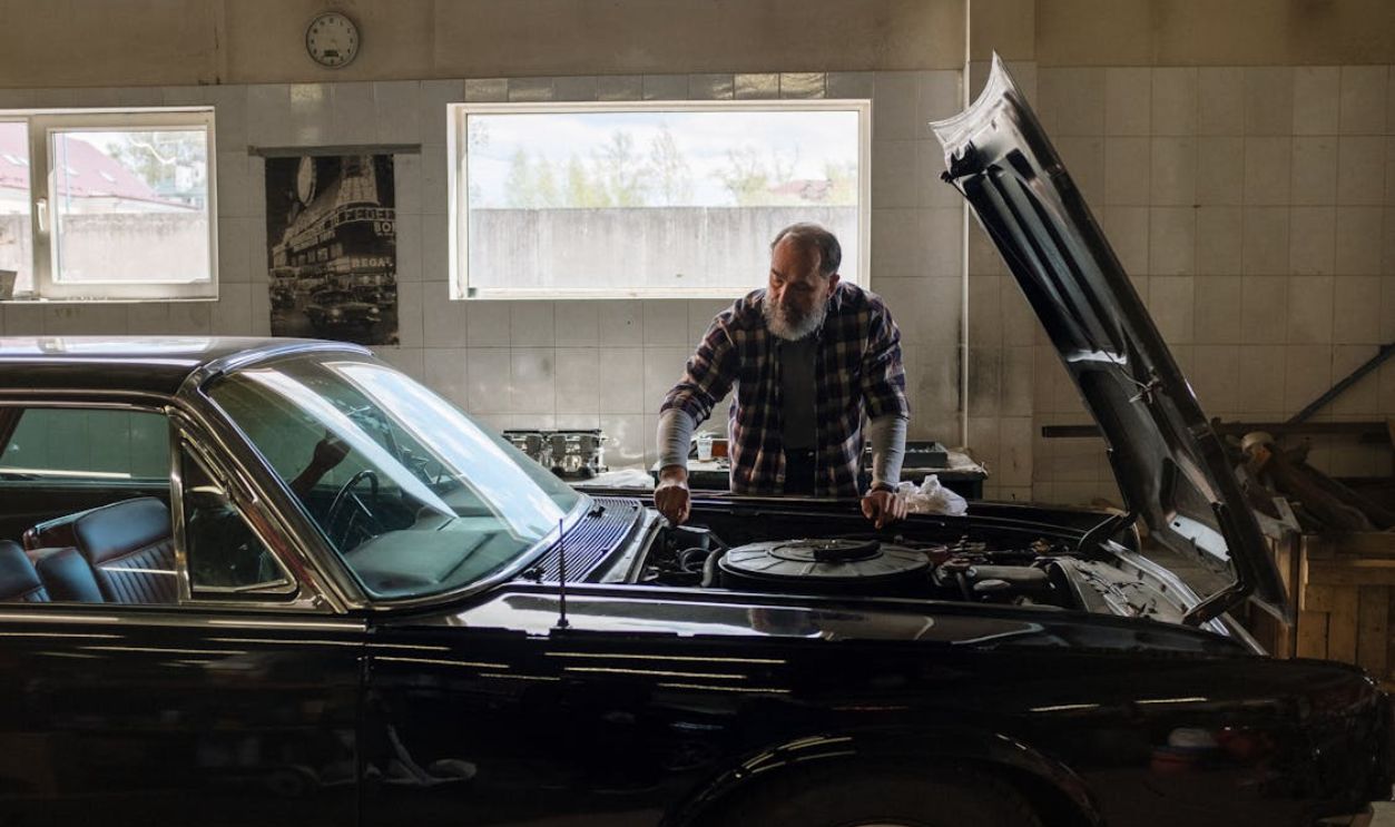 Man in Black and White Checkered Dress Shirt Standing Beside Black Car