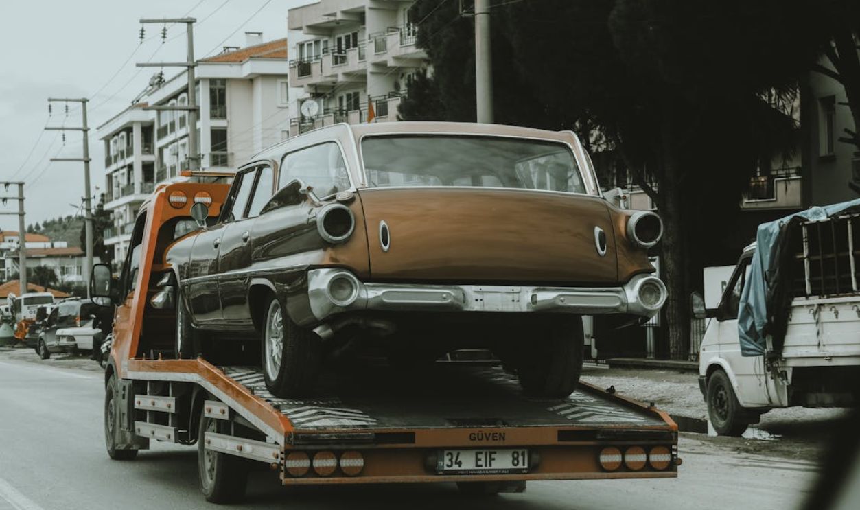A Tow Truck Crane Carrying Vintage Car while Moving on the Road