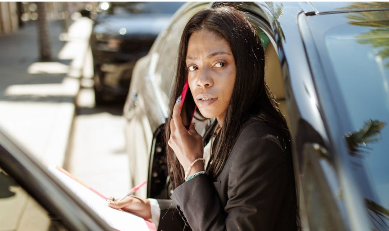 Woman Sitting on the Car While Talking on the Phone