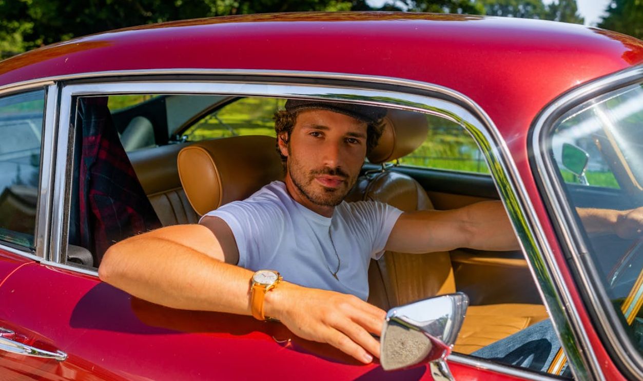 Man in White Polo Shirt Sitting on Red Car Seat