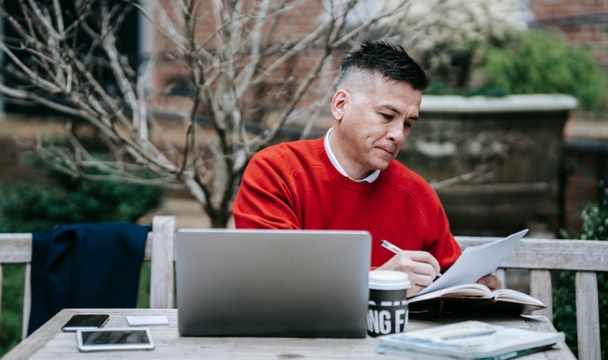 Photo Of Man Reading On Paper