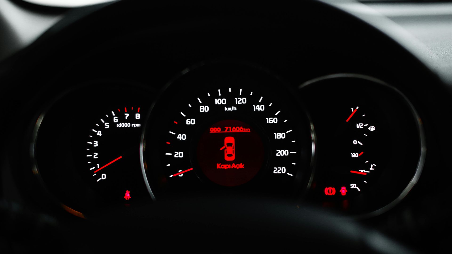 Car dashboard showing a warning light with various dials and gauges in focus.