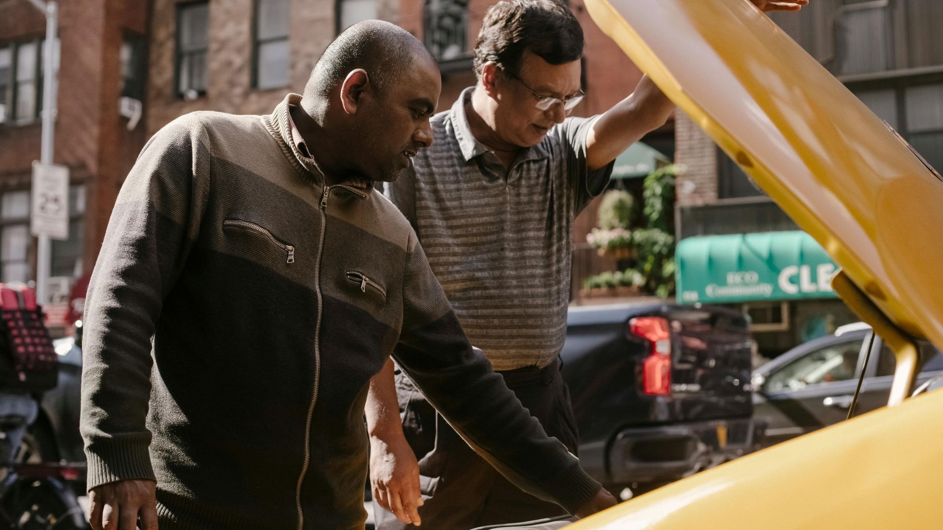 Focused multiracial male friends in casual clothes standing near opened hood of vehicle and looking at details