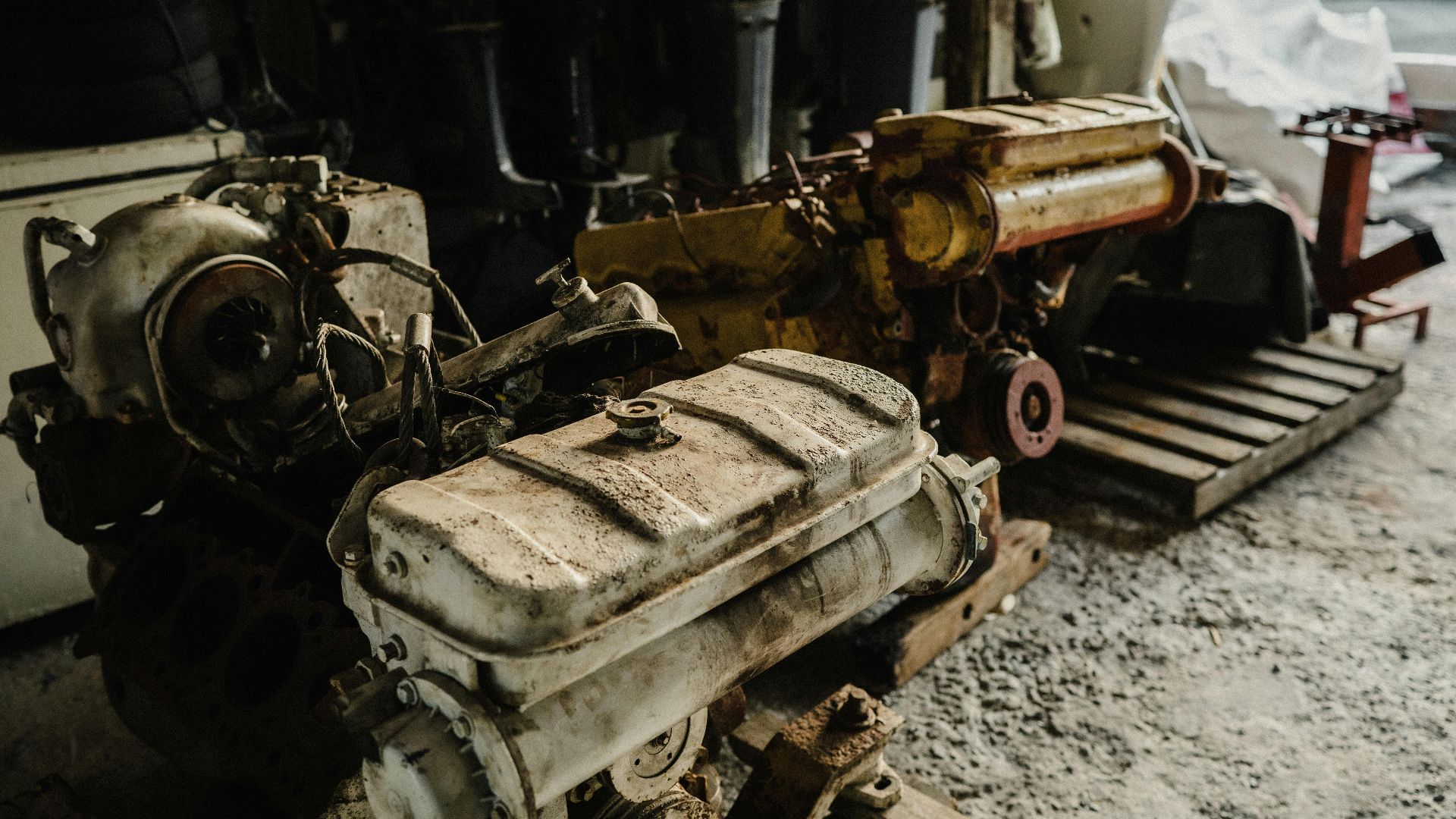 A collection of used car engines stored in an industrial workshop setting.