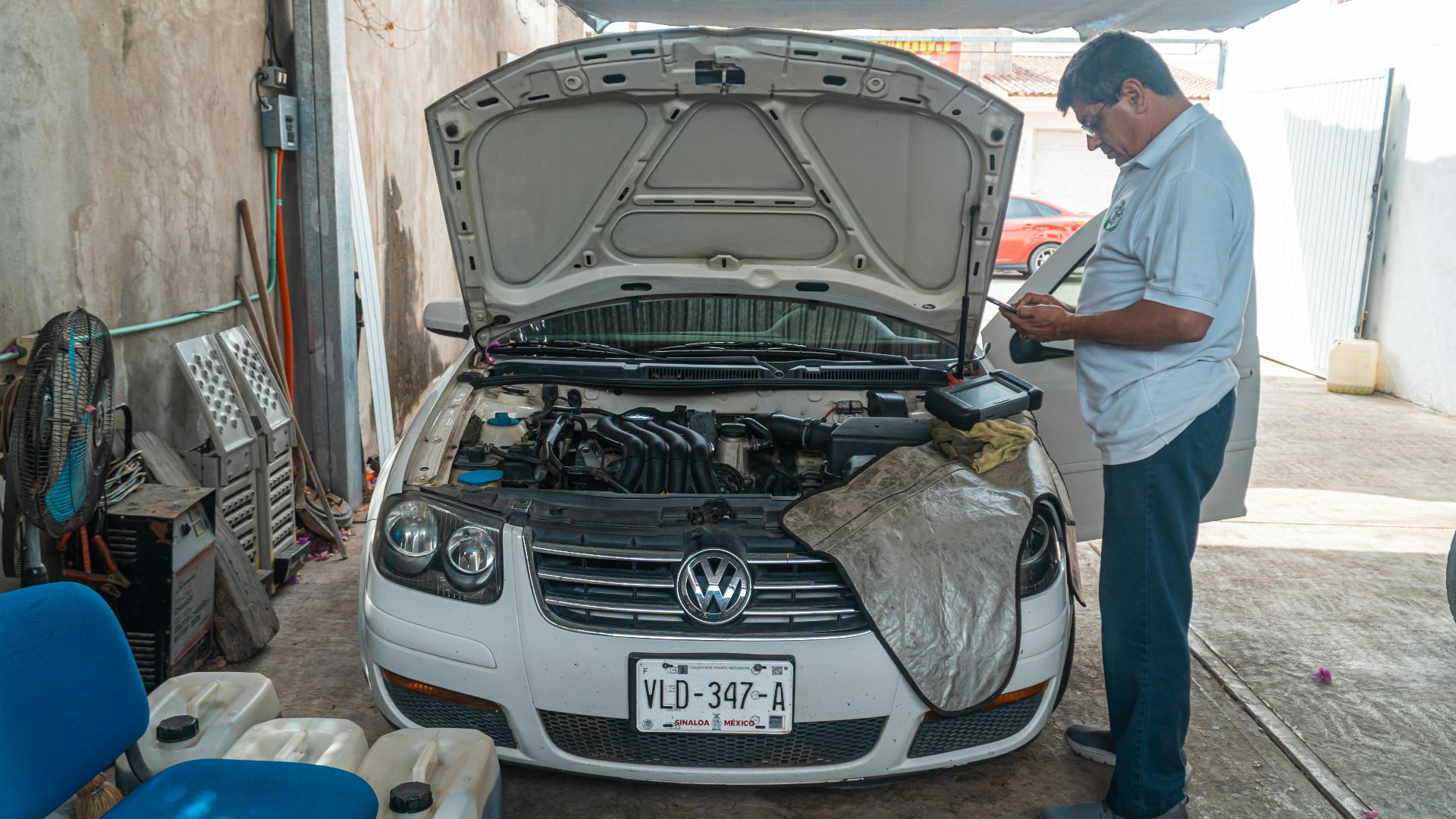 A mechanic examines a Volkswagen engine in a garage setting, focusing on car maintenance.