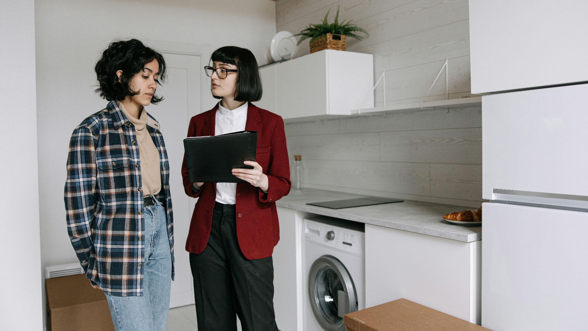 Real estate agent discussing home details with a client in a modern kitchen setting.