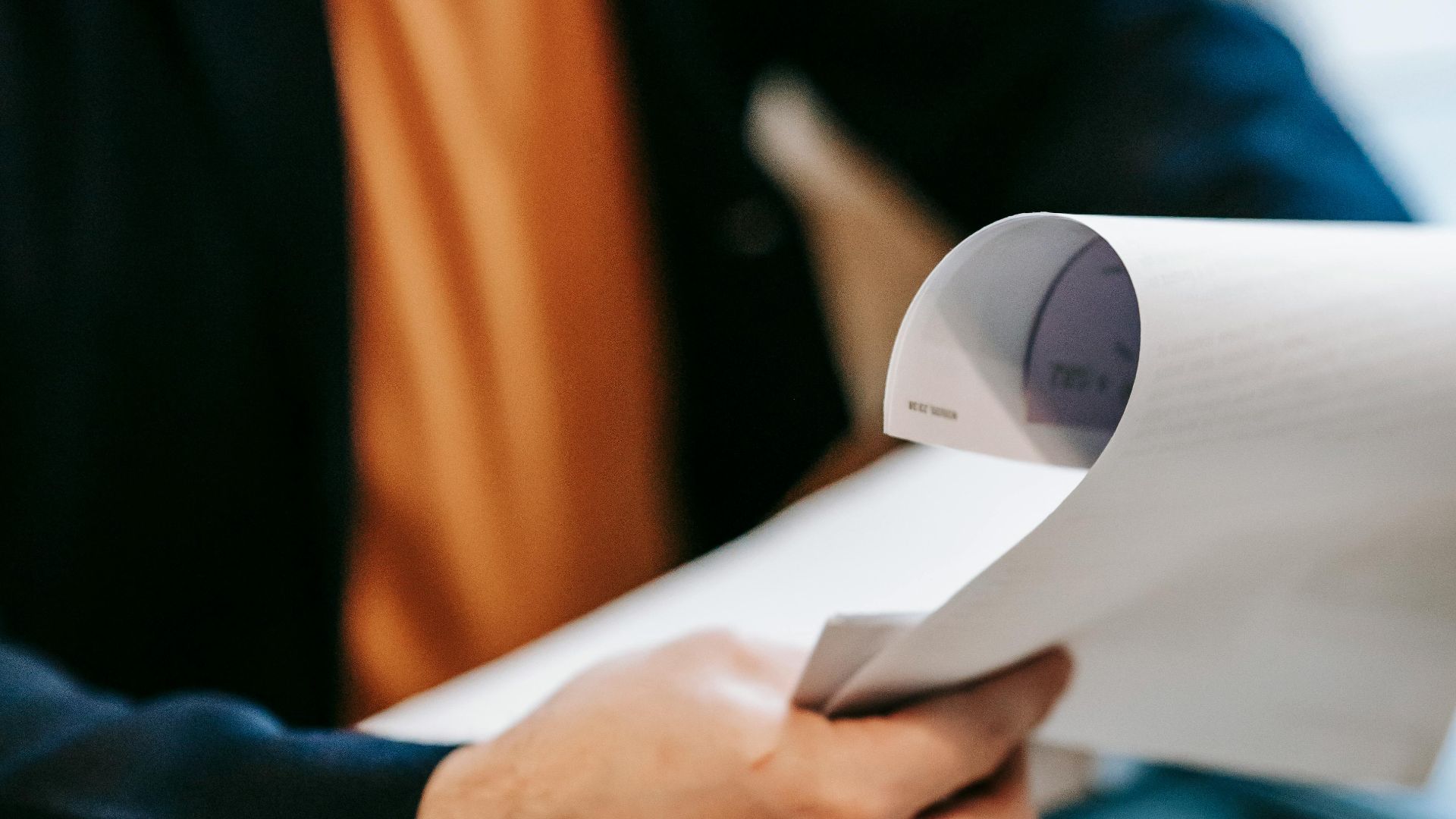 Business professional reviewing important documents indoors. Hands focus, blurred background.