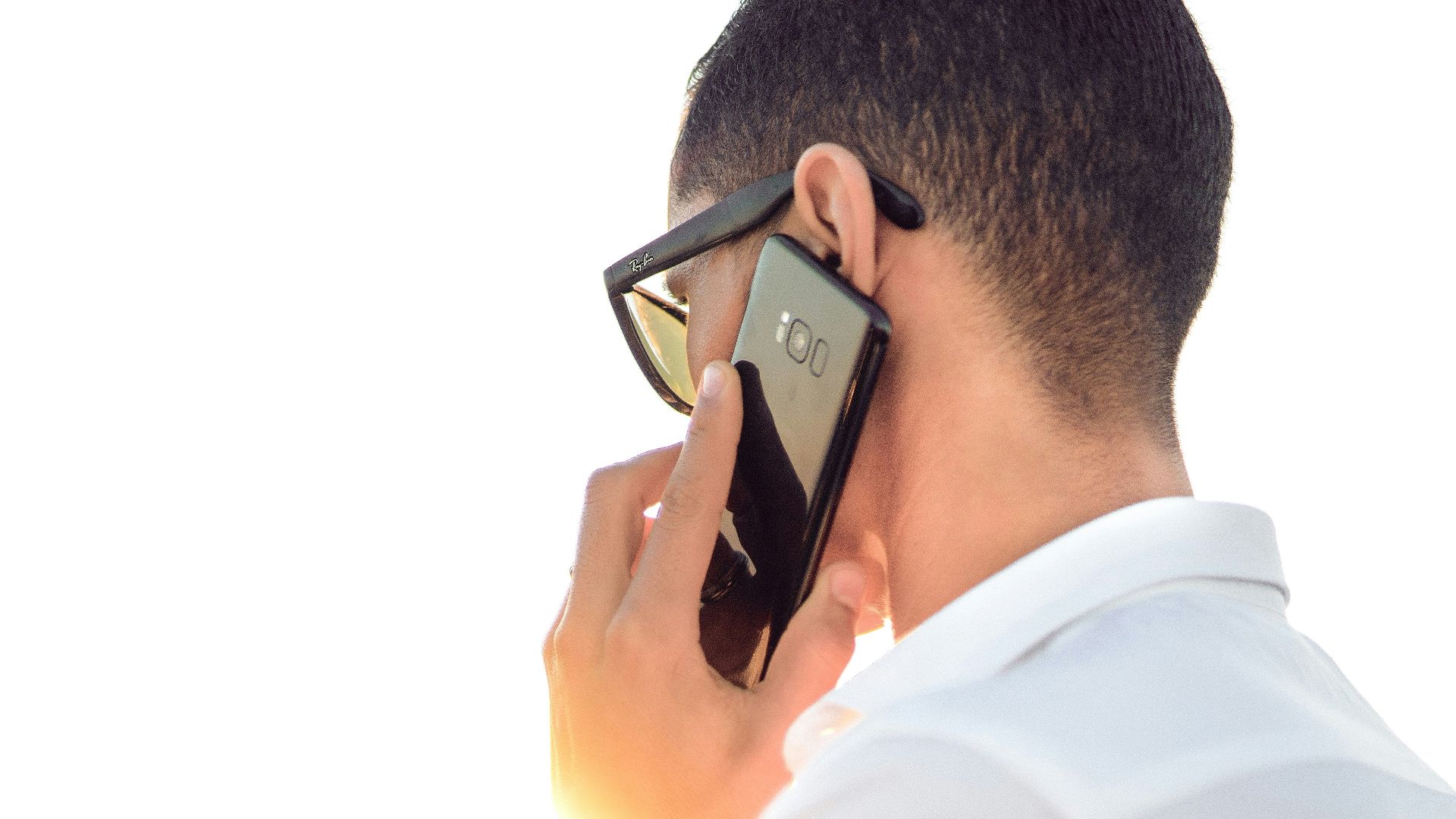 man holding smartphone standing in front of calm body of water