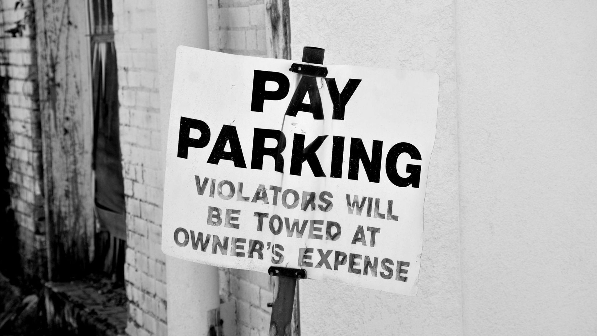 A black and white photo of a pay parking sign in downtown Tyler, Texas. Violators will be towed.