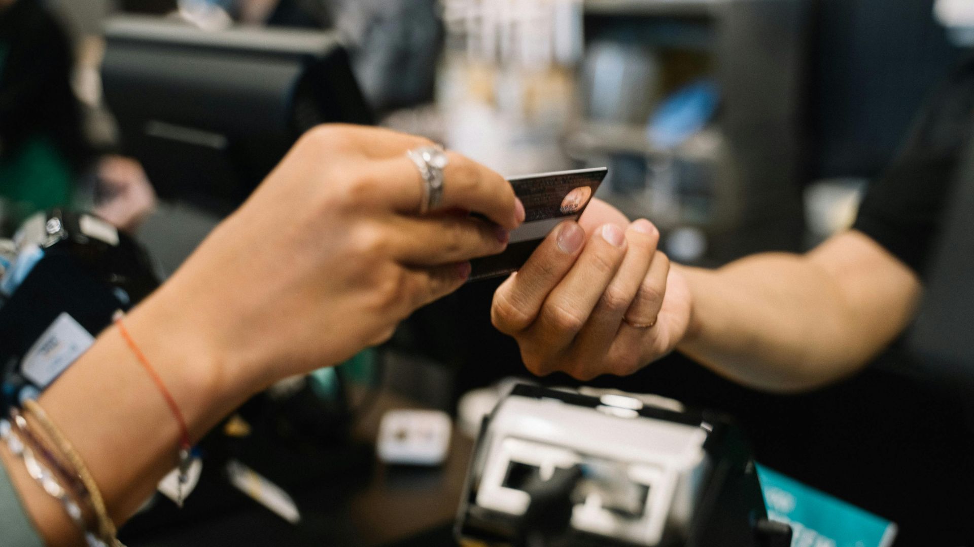 Close-up of hands completing a payment transaction at a retail checkout using a bank card.