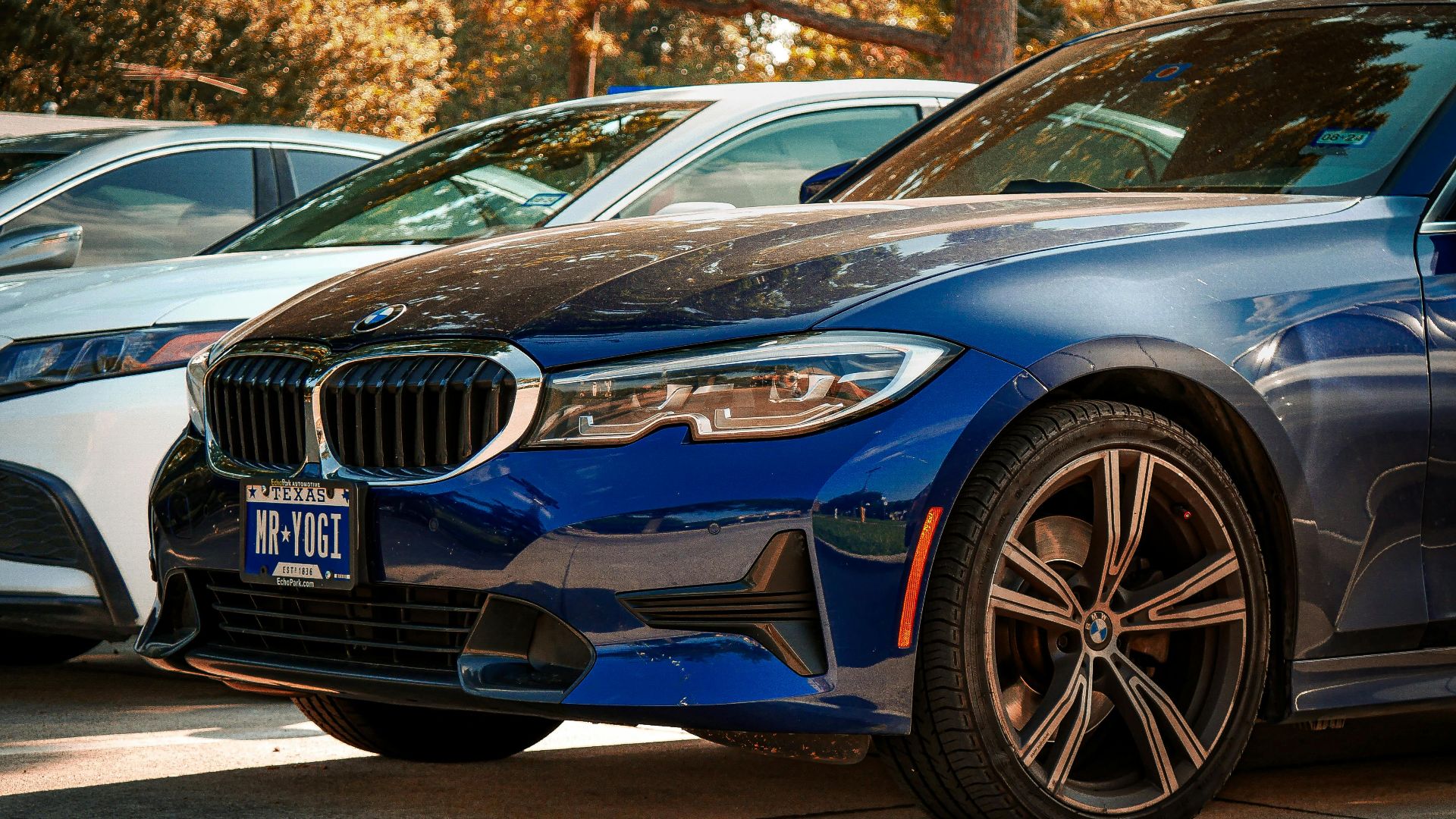 Blue BMW 330i parked outdoors in Arlington, Texas, under sunny skies.