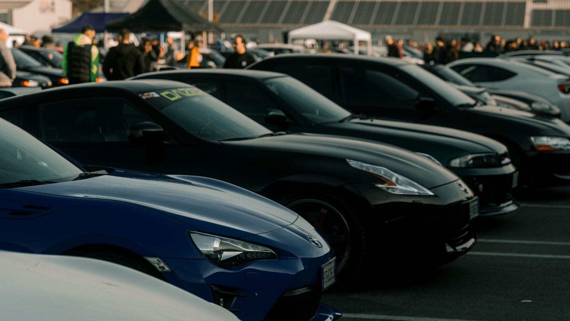 Lineup of sports cars at an outdoor event in Cremona, Italy, showcasing automotive diversity.