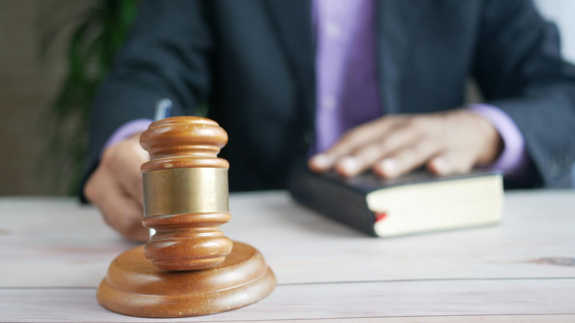 A wooden gavel and legal book represent justice in a court setting, emphasizing order and legal authority.