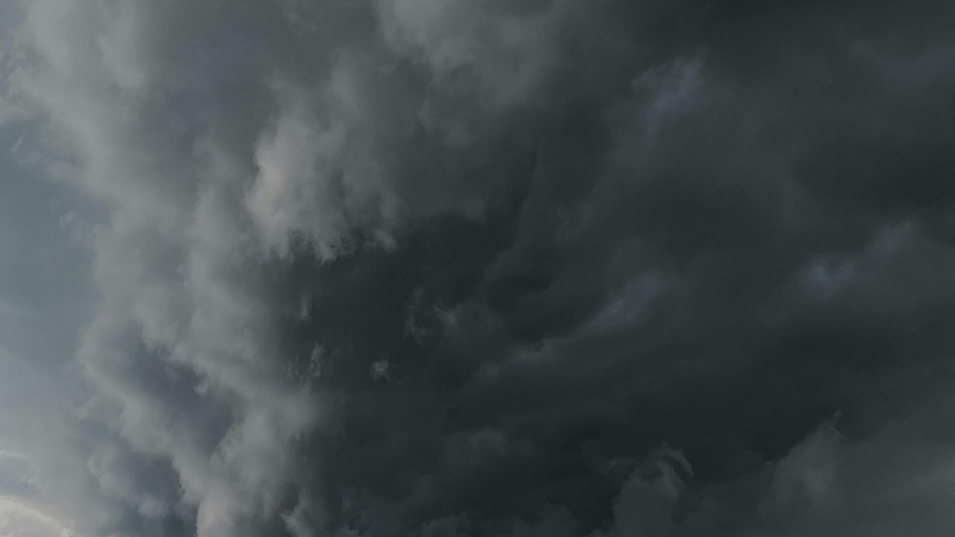 A dramatic vertical shot of dark storm clouds filling the sky, suggesting an impending storm.