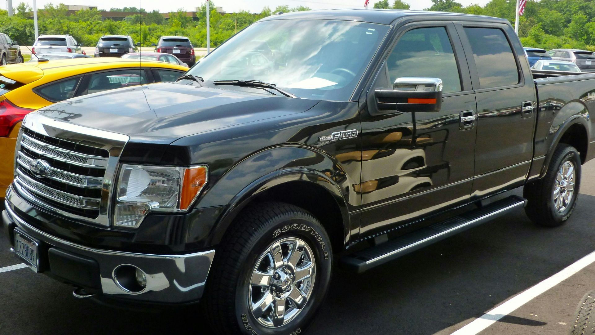 Black Ford F-150 pickup truck displayed at an outdoor dealership lot on a sunny day.
