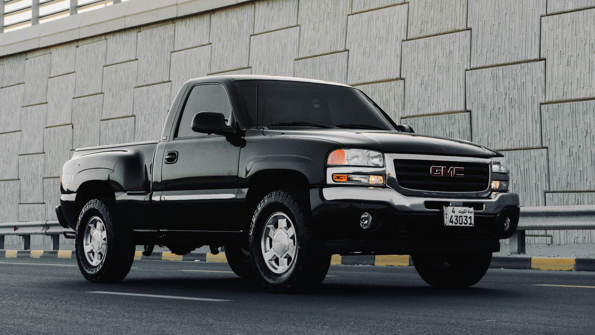 Sleek black pickup truck parked on an urban road under a concrete overpass in daylight.