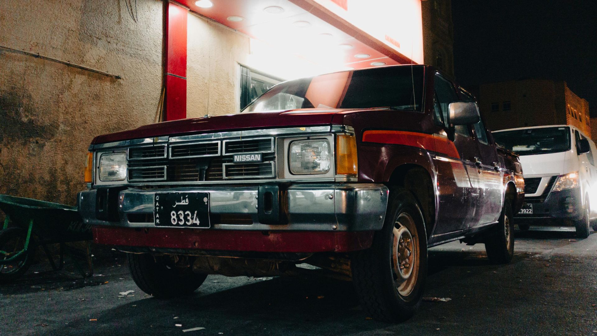An iconic Nissan pickup truck captured at night in the vibrant streets of Doha, Qatar.