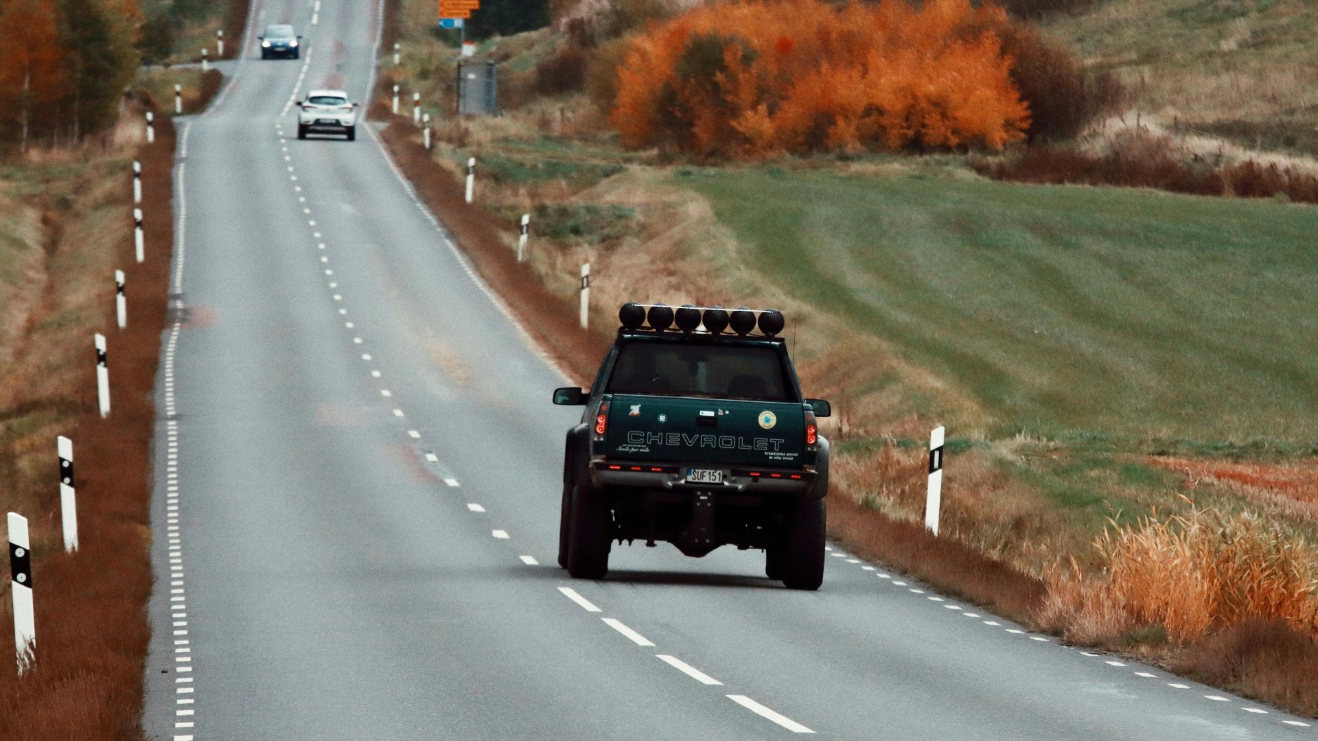 Pickup truck driving on a winding road in Huskvarna, Sweden, during autumn.