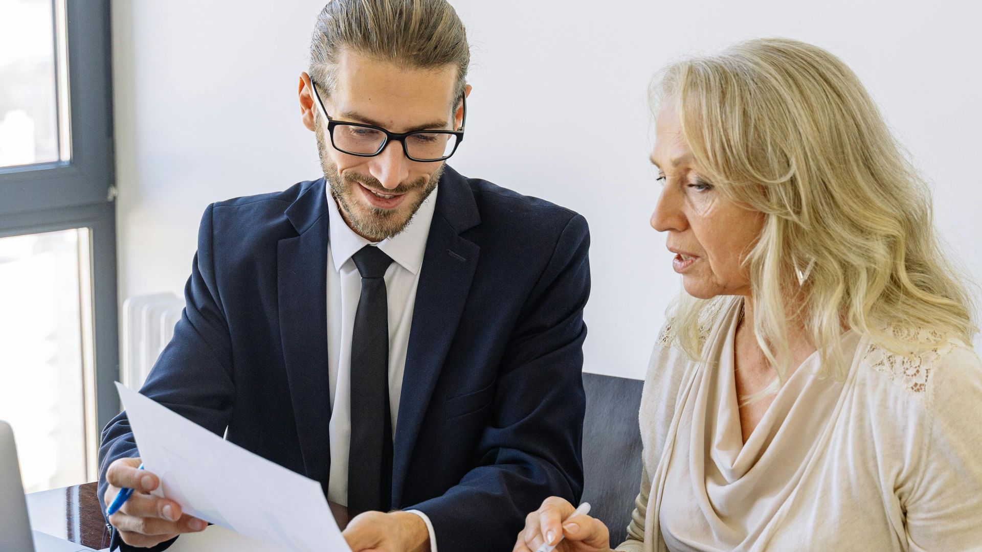 Two business professionals reviewing financial documents and graphs during a meeting.