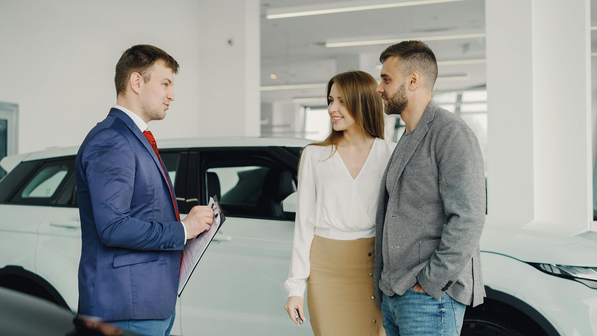A couple discussing car purchase options with a salesperson in a modern showroom.