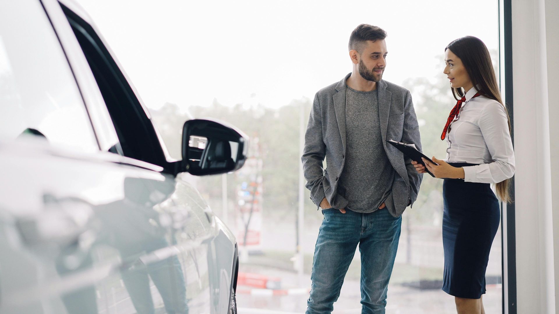Man consulting with car salesperson in a showroom, discussing car options.