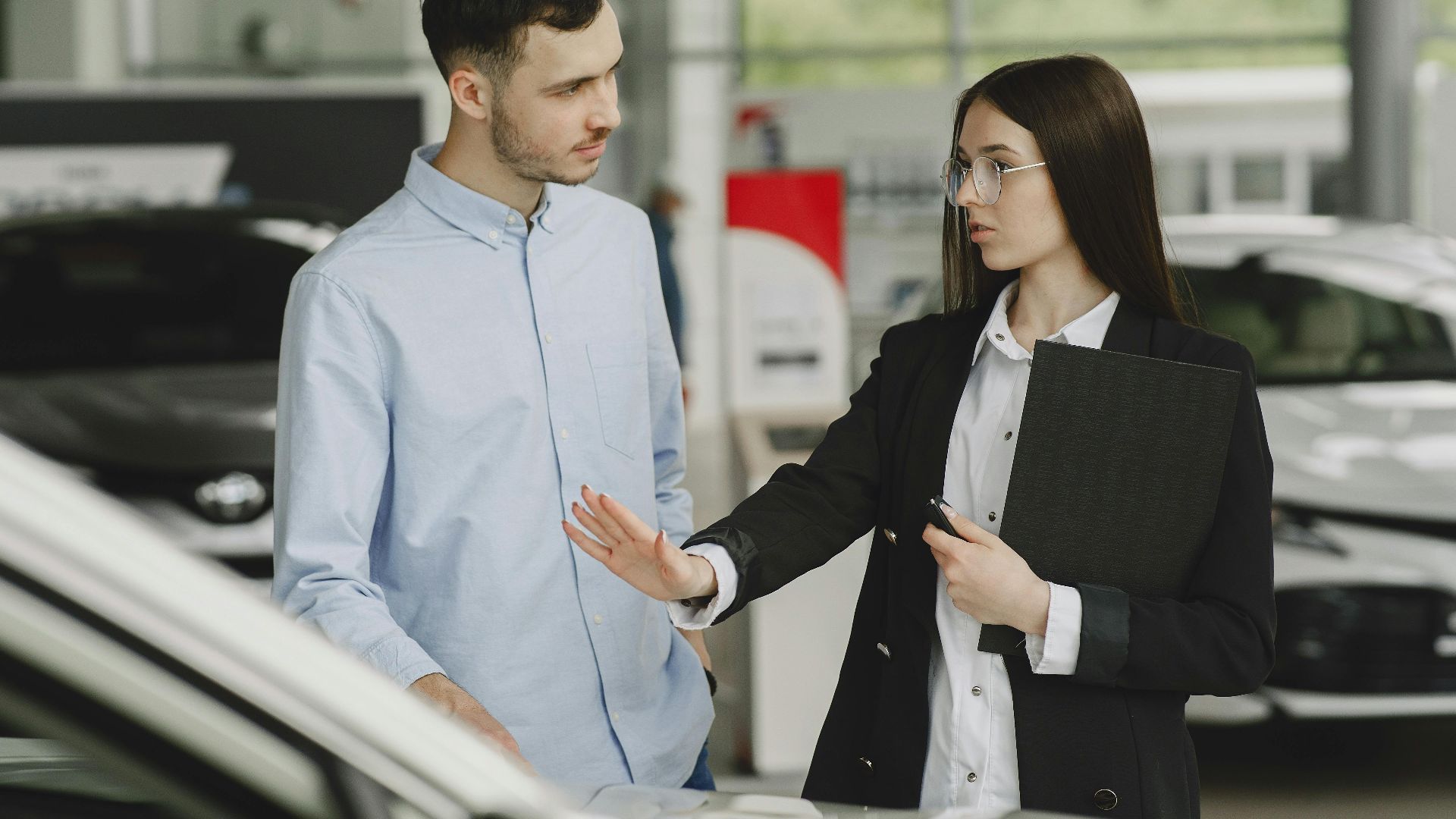 A salesperson and customer discussing car features in a dealership setting.