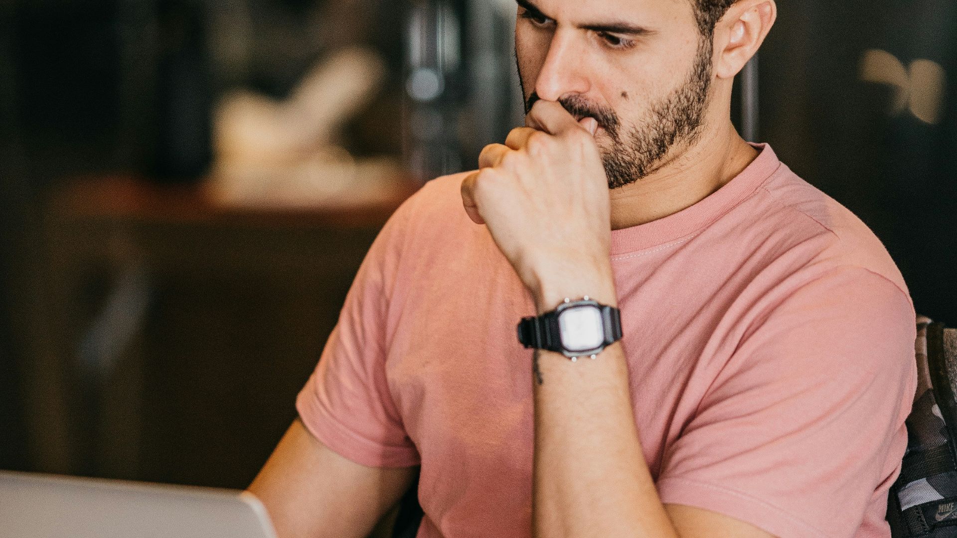 a man sitting at a table with a laptop and a cup