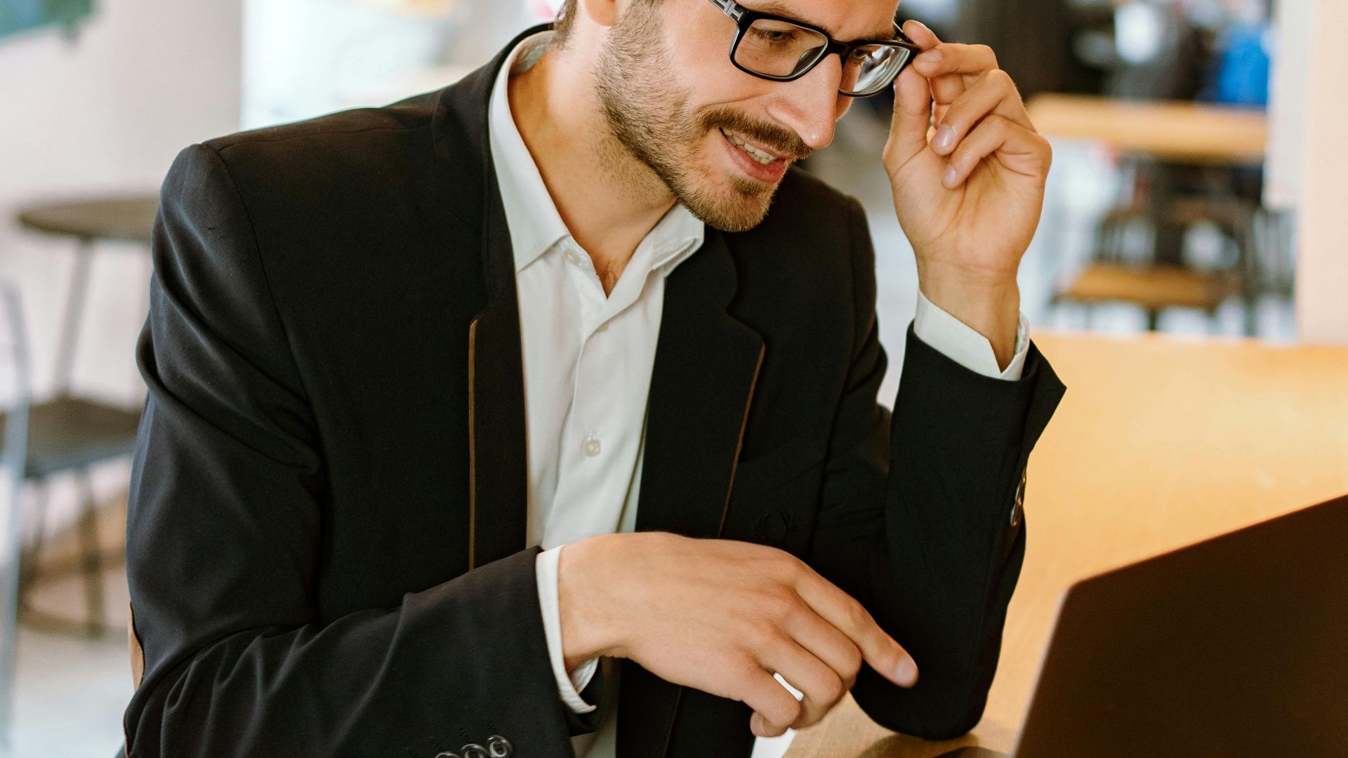 Businessman with glasses working on a laptop in a stylish modern office setting.