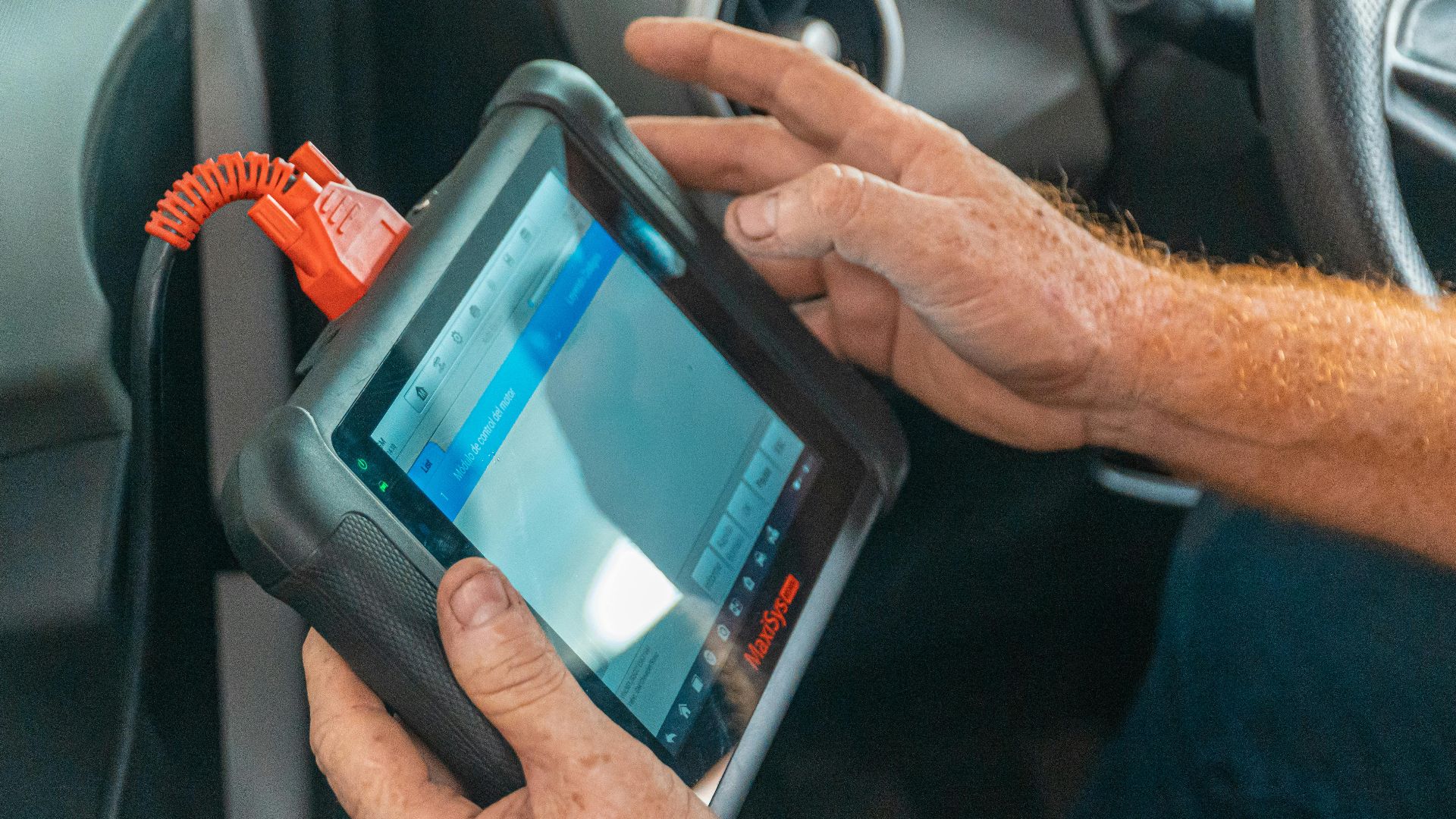 A mechanic uses a diagnostic tablet inside a car for vehicle analysis.