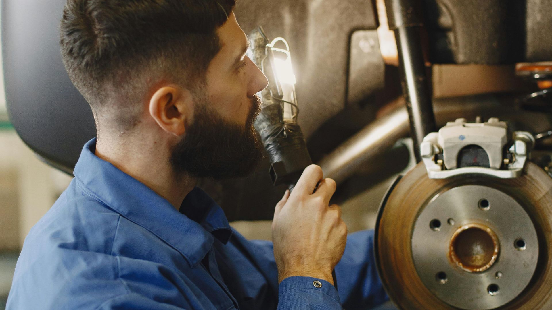 Auto mechanic conducting brake inspection at repair shop with focused attention.
