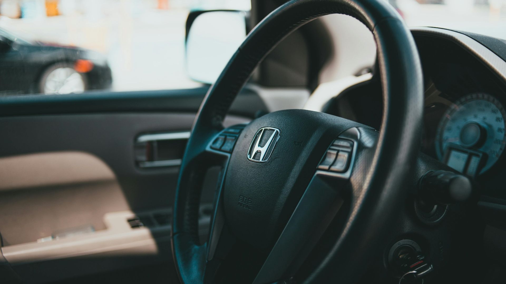 Close-up shot of a car steering wheel with dashboard, showcasing vehicle interior details.