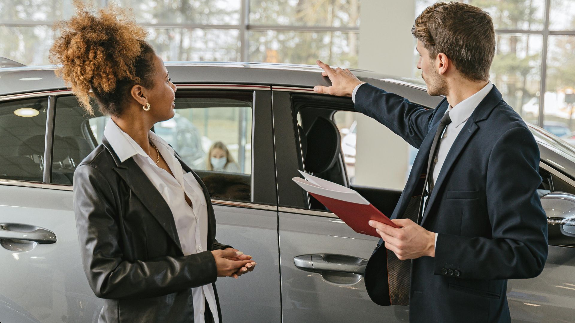 A woman and a car salesman discuss vehicle options inside a dealership.