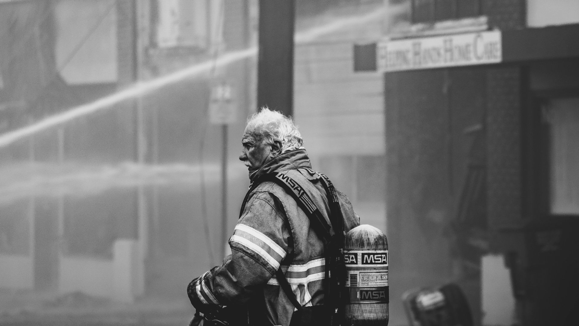 Heroic firefighter in protective gear managing a city fire, showcasing bravery and resilience.