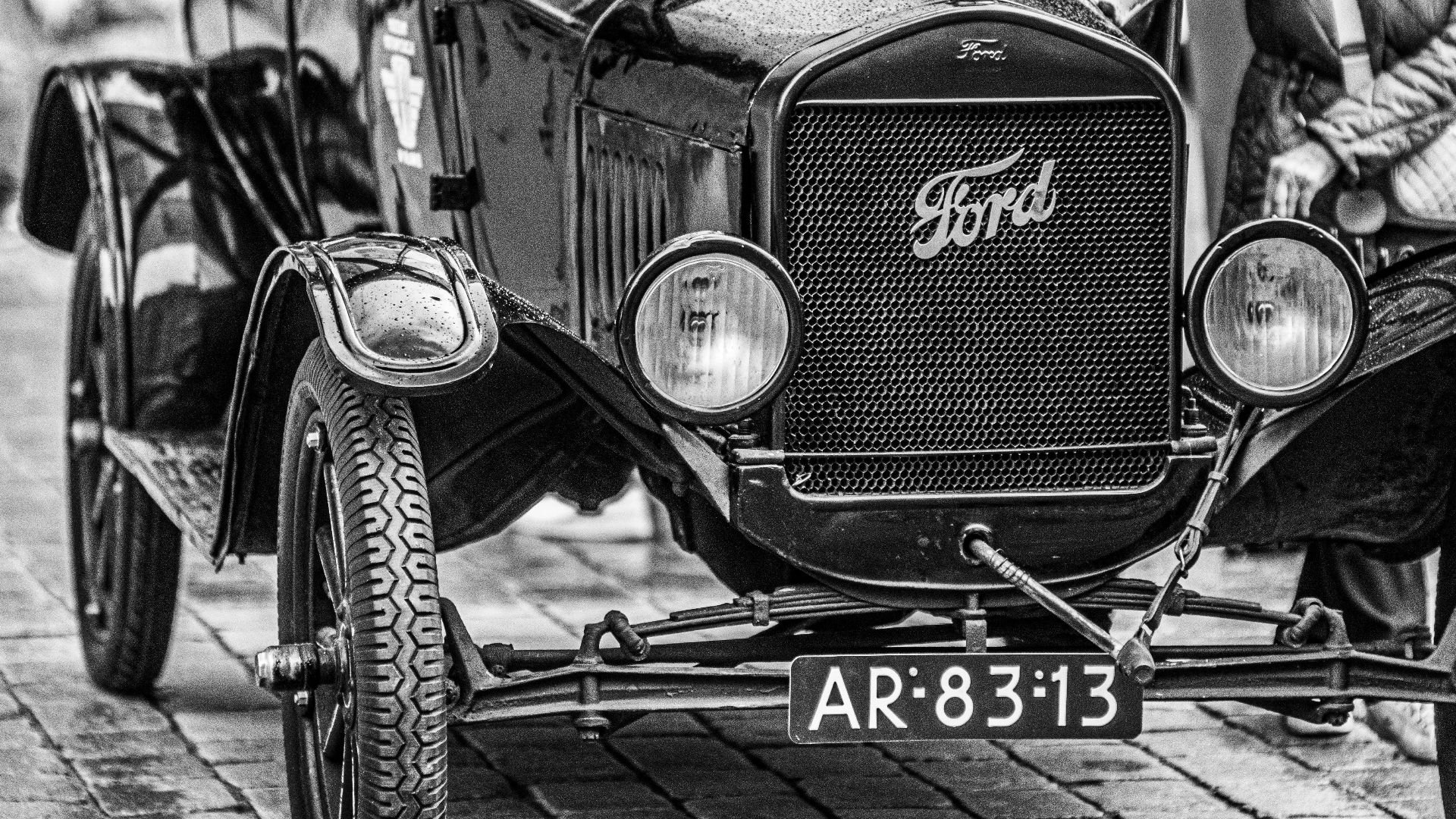 Classic Ford Model T car displayed on cobbled street, black and white photo.