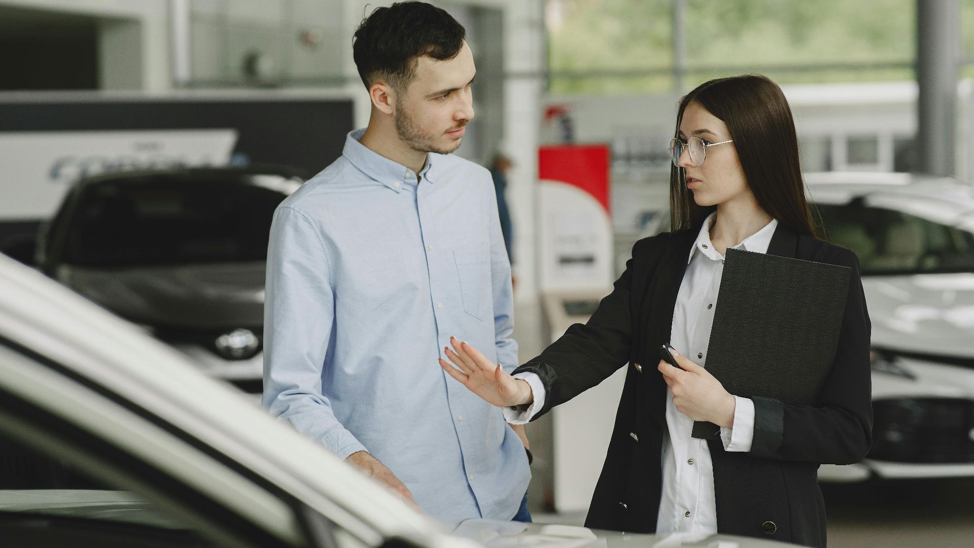 A salesperson and customer discussing car features in a dealership setting.