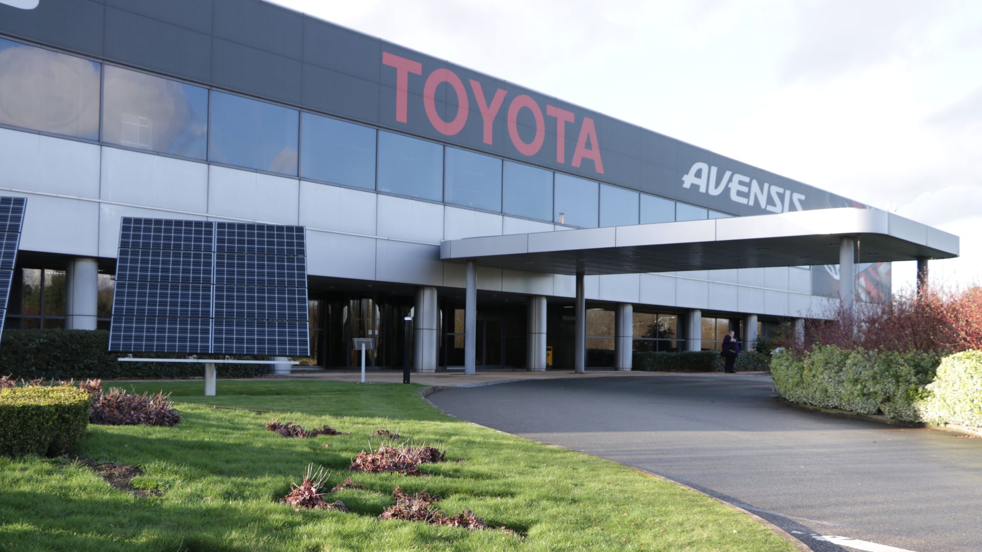 Main reception entrance to Toyota Motor Manufacturing plant at Burnaston near Derby, England. A set of three small solar panel arrays beside the entrance indicates the plant's use of renewable energy by means of its on-site 4.1MW array of over 16,500 PV units.