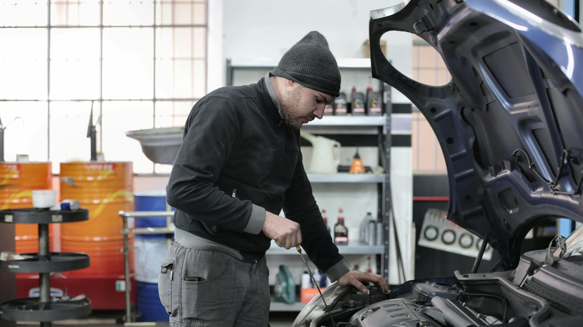 Mechanic checking a car engine in a garage, ensuring quality maintenance and repair.