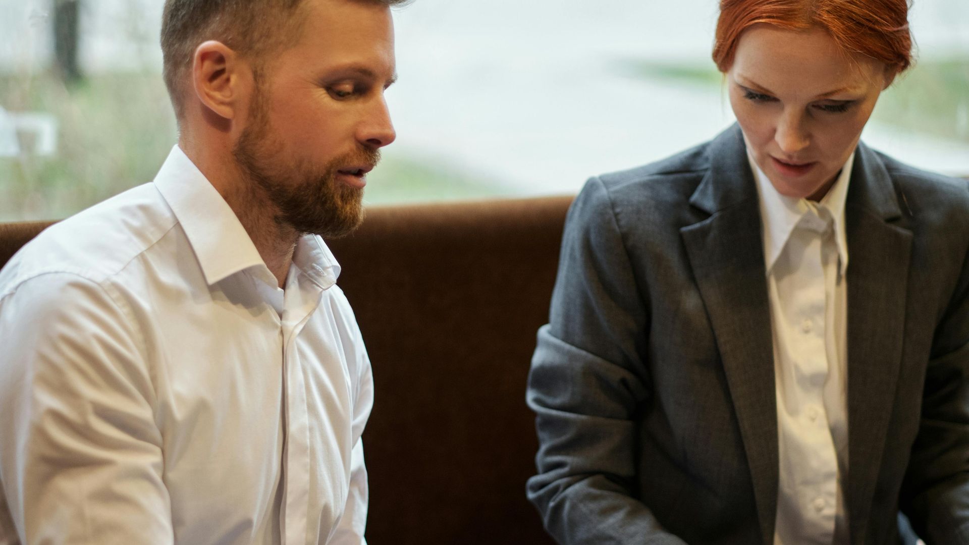 Two business professionals discussing work over coffee in a cafe setting.