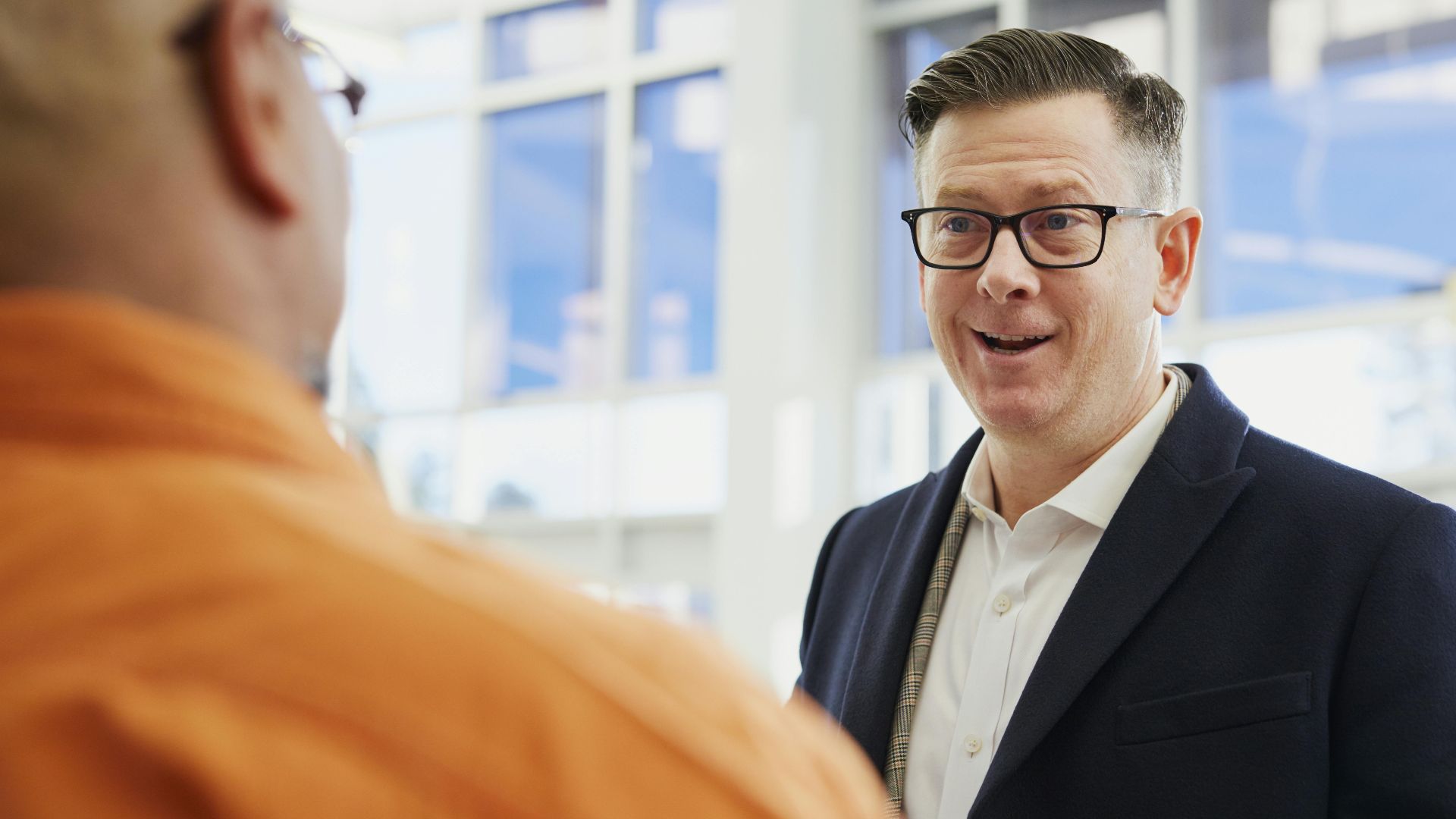 Two business professionals engaged in a conversation in an office setting.