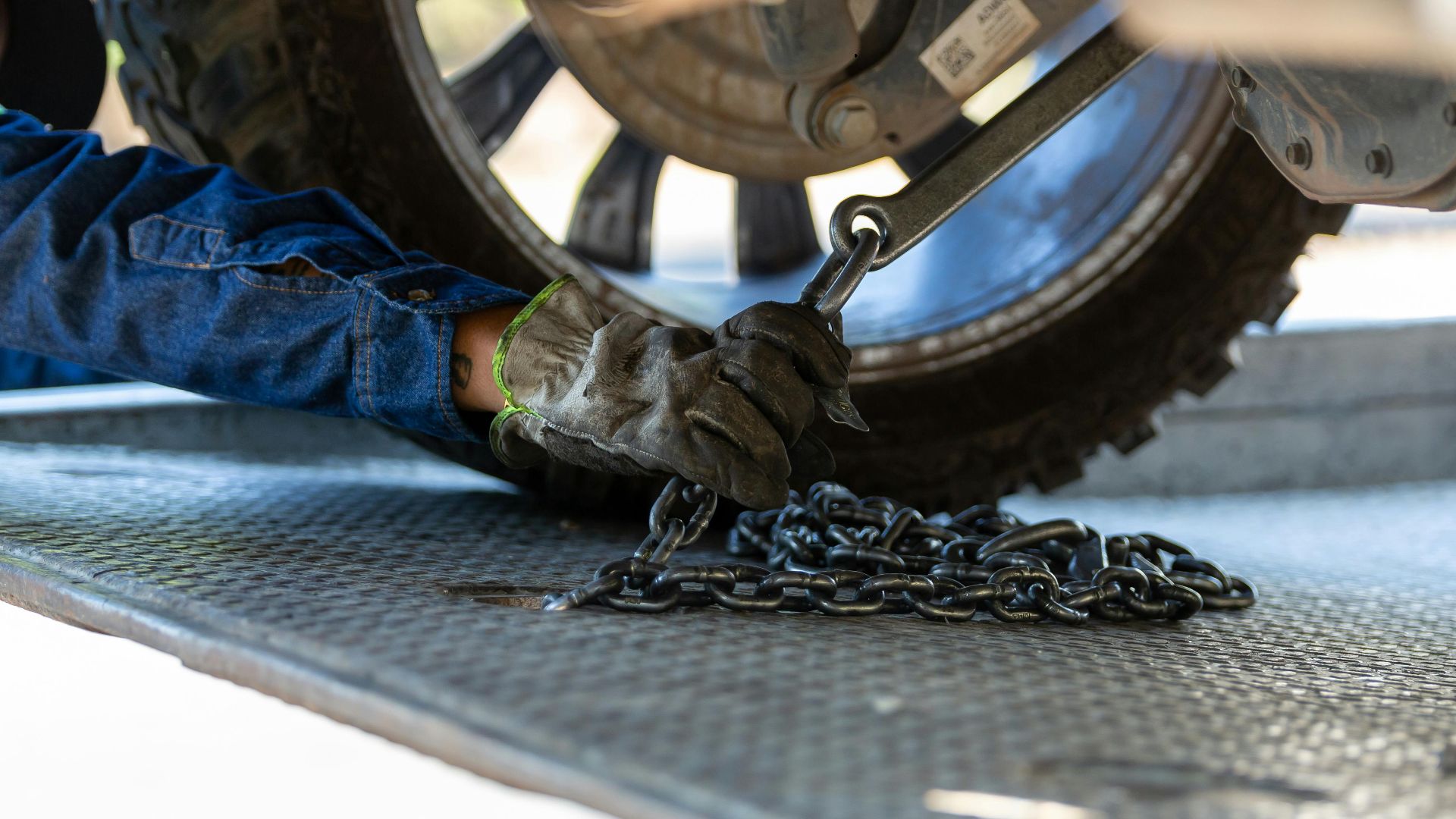 Mechanic securing a vehicle on a service platform with a chain for safe towing.