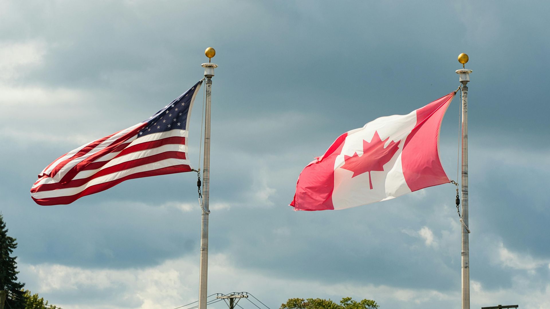 Canadian and American flags waving under a cloudy sky in Harbor Beach, MI.