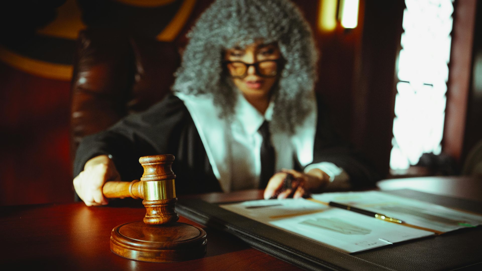 Female judge in a courtroom setting, focusing on legal documents with a gavel.