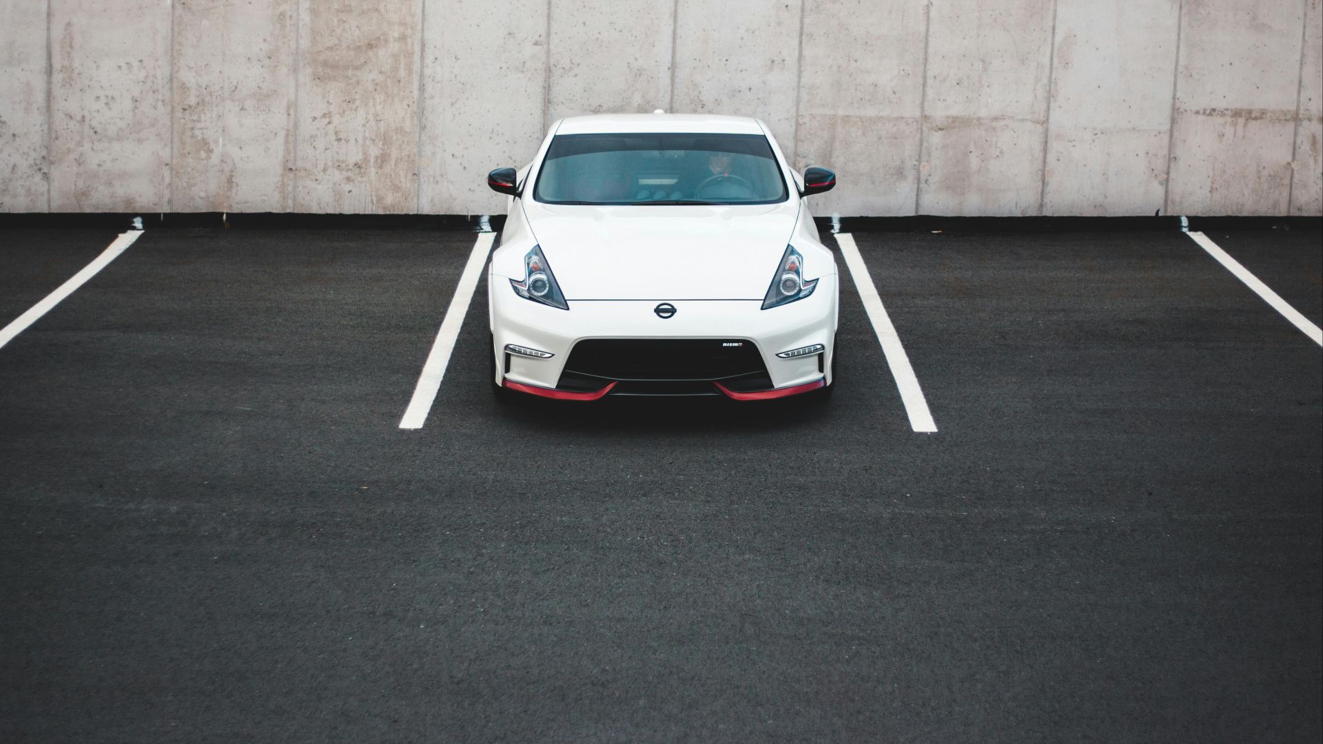 From above of contemporary design new auto parked on asphalt pavement with marking lines in city parking lot near shabby wall in daylight