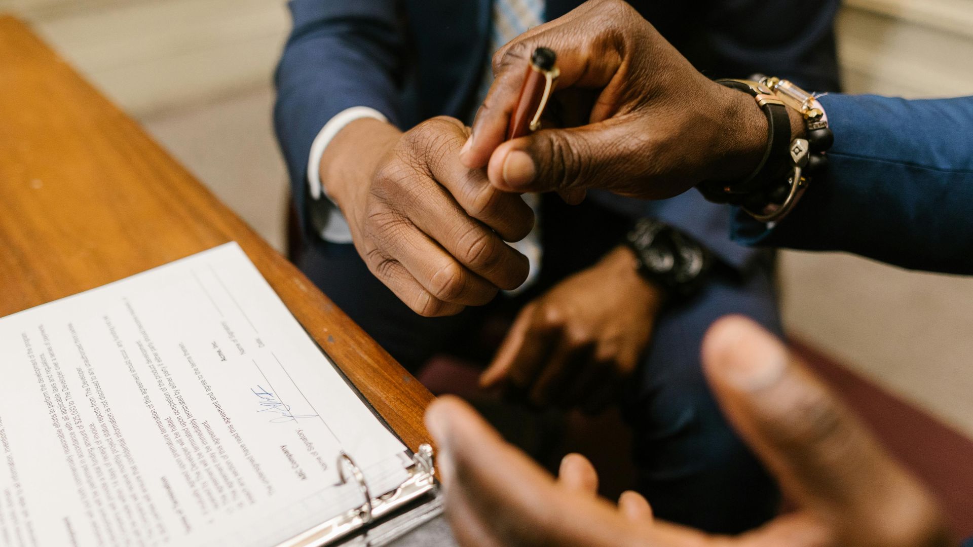 Two businessmen in suits finalize a contract, highlighting teamwork and agreement.