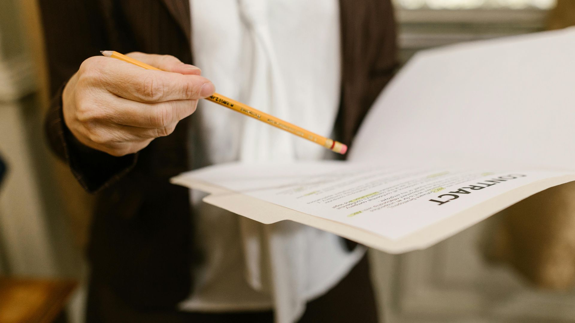 A businesswoman holds a contract, pointing with a pencil. Legal and corporate setting.