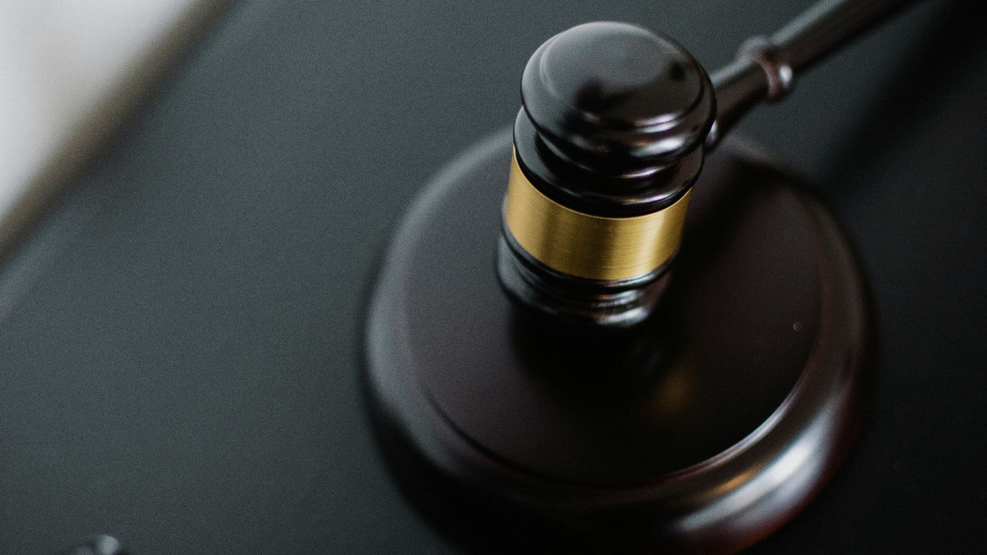 From above of wooden gavel on round surface near folders on table in courtroom