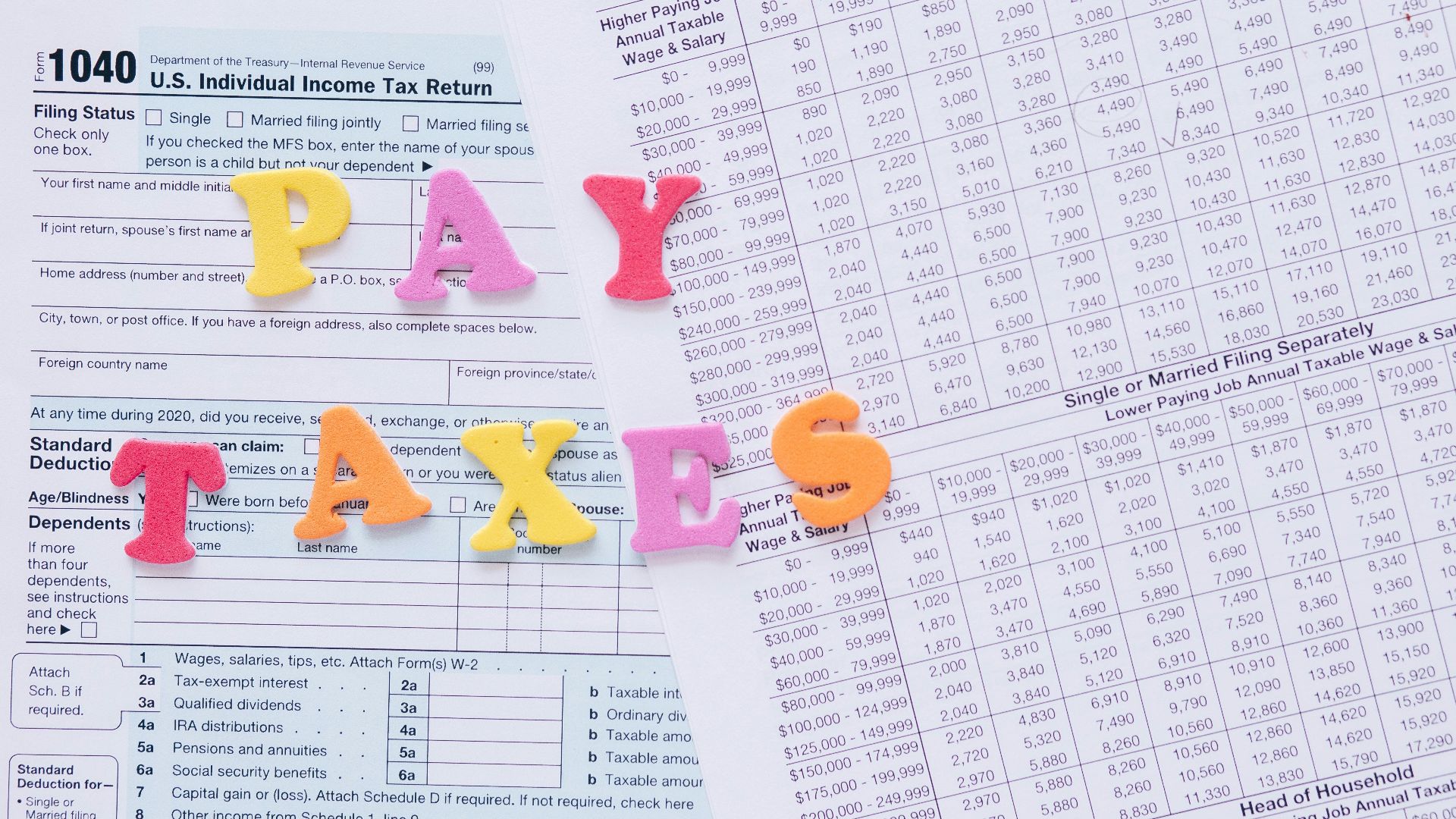 Close-up of U.S. tax forms with colorful 'PAY TAXES' letters emphasizing financial deadlines.