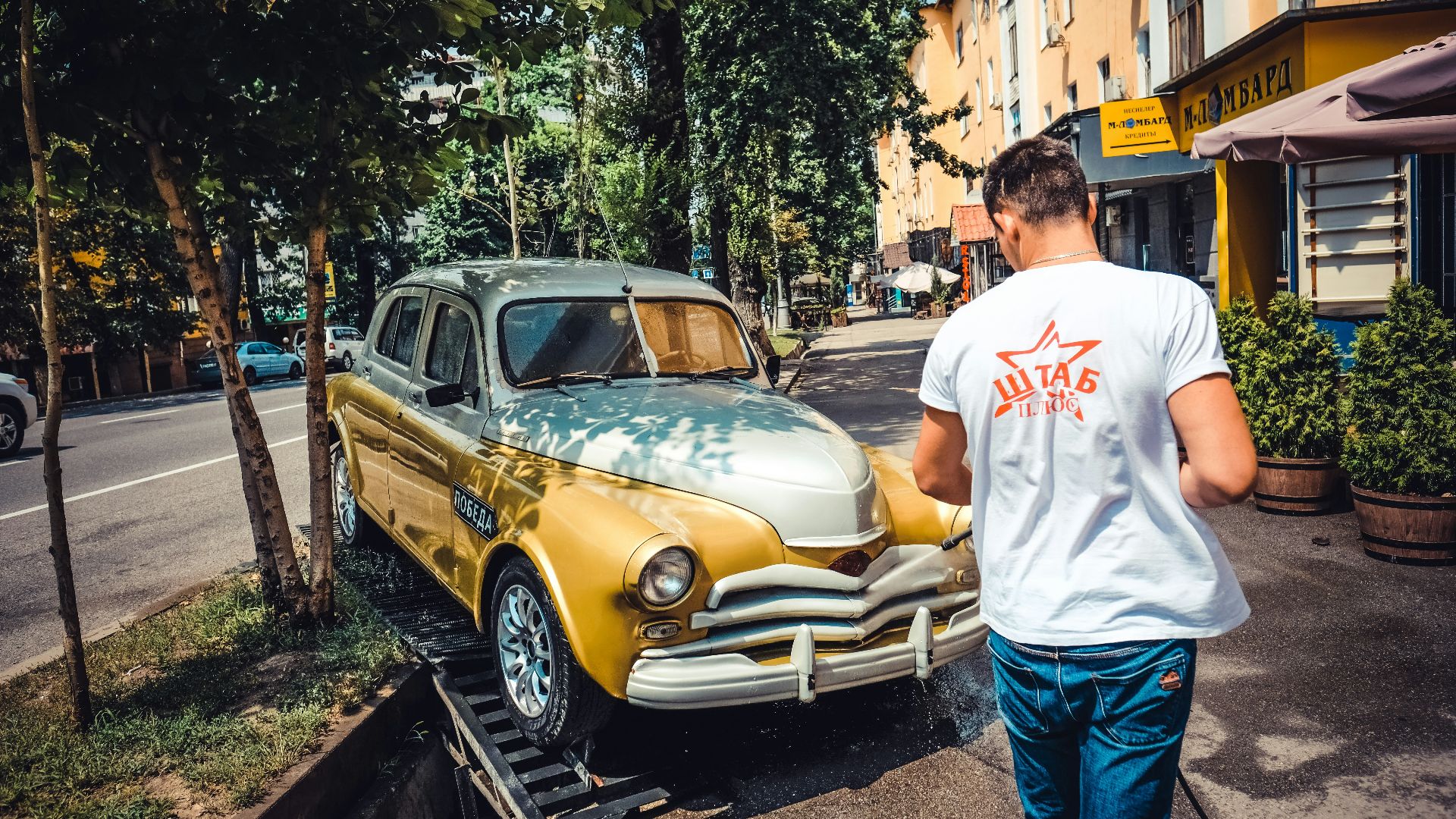 man in white shirt and blue denim jeans standing beside yellow car during daytime