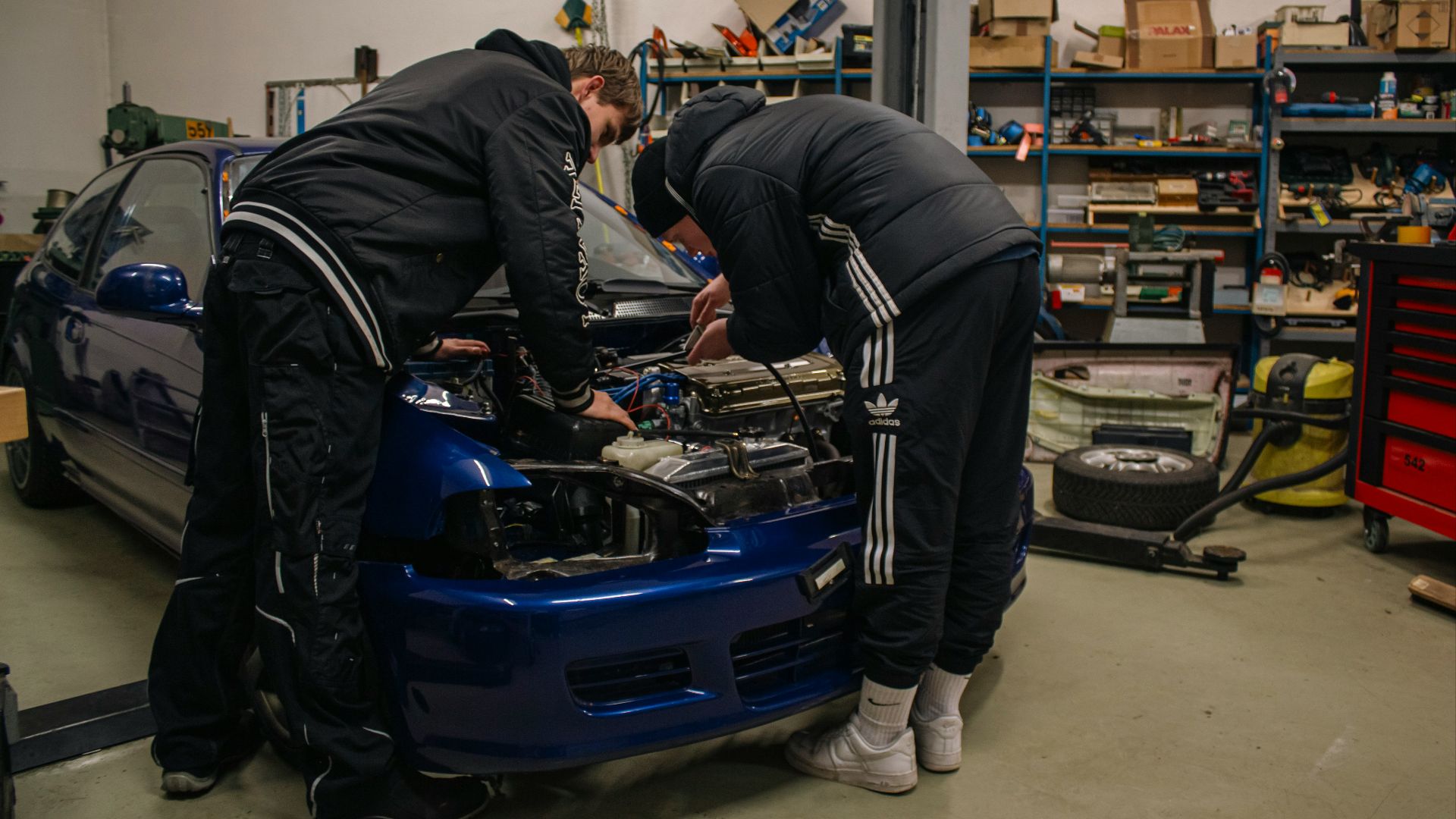 Two men working on a car in a garage